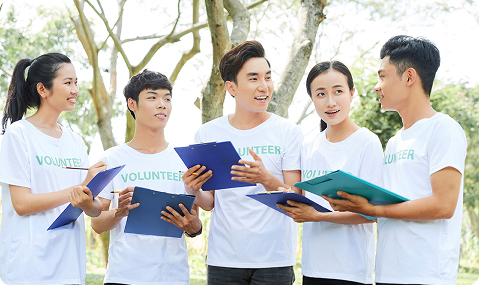 ボランティアTシャツを着た若者5人が笑顔で話し合っている様子